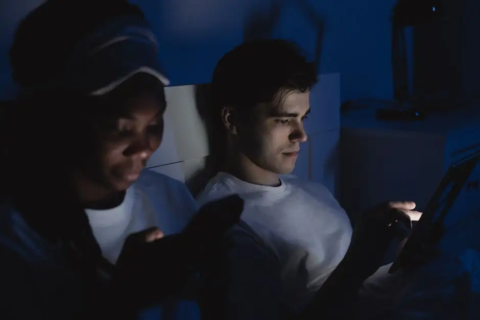 Personne consultant son smartphone dans un lit sombre, visage éclairé par la lumière bleue de l'écran